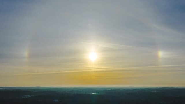 Rare optical sun dog parhelion effect with glowing light halo over scenic landscape at golden hour during colorful sunset