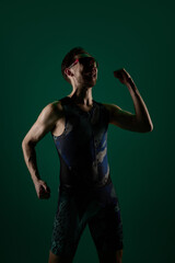 Fototapeta premium Male athlete celebrating with clenched fist and raised arm in studio lighting. Concept of winning moment visuals, success celebration content, motivation energy, achievement and confidence.