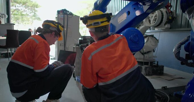 Robotic technicians use clamp meter to measure current within robotic arm. Troubleshooting process, aimed at diagnosing electrical issues, shorts, overloads, inefficiencies in electrical system.
