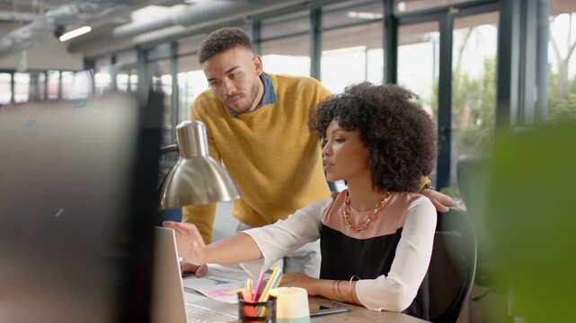Woman clicking while man approaching, leaning, placing hand on chair, pointing monitor for design
