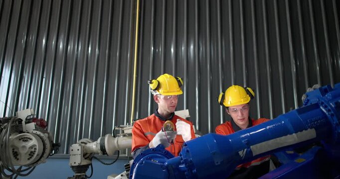 Robotic technicians use clamp meter to measure current within robotic arm. Troubleshooting process, aimed at diagnosing electrical issues, shorts, overloads, inefficiencies in electrical system.
