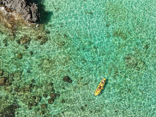 Aerial drone view of kayakers paddling through the crystal-clear turquoise waters of Big Lagoon in El Nido, Palawan, Philippines. © akturer