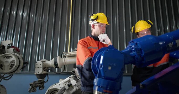 Robotic technicians use clamp meter to measure current within robotic arm. Troubleshooting process, aimed at diagnosing electrical issues, shorts, overloads, inefficiencies in electrical system.
