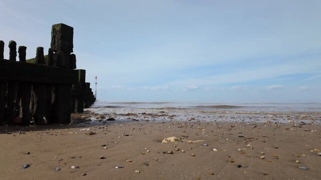 Hunstanton, Norfolk, England, UK - By the breakwater at the beach, waves calming rolling in, and natural sounds.