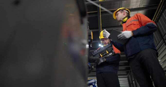 Robotic technicians use clamp meter to measure current within robotic arm. Troubleshooting process, aimed at diagnosing electrical issues, shorts, overloads, inefficiencies in electrical system.
