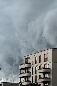 Storm clouds tower behind a vertical apartment building residential balconies in Gallus Frankfurt Europaviertel creating dramatic urban mood