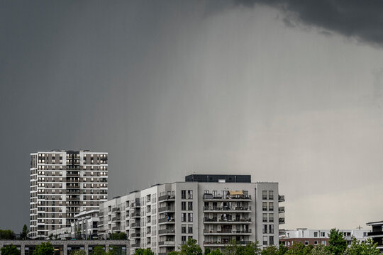 Storm rain clouds surround a residential apartment tower in Gallus Frankfurt Europaviertel showing architecture on summer day street