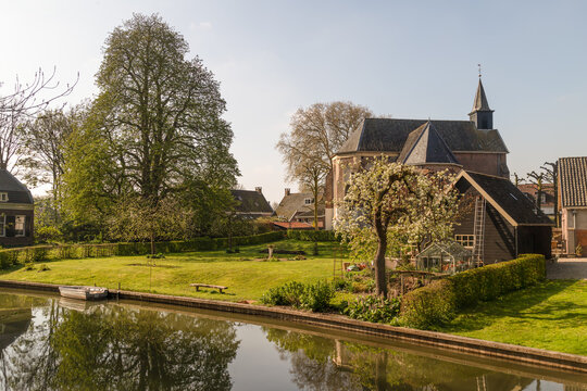 Picturesque view of a small church by the water in the historic village of Cothen in the Netherlands during spring.