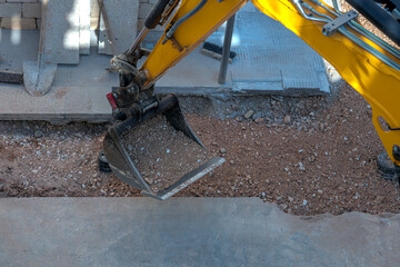 Close-up of a yellow excavator bucket filled with gravel at a construction site. Professional heavy machinery and earthmoving equipment for industrial and infrastructure projects. © peuceta