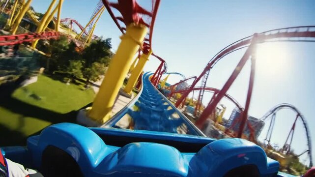 Roller coaster POV ride over a blue track with red supports on a bright sunny day at a theme park
