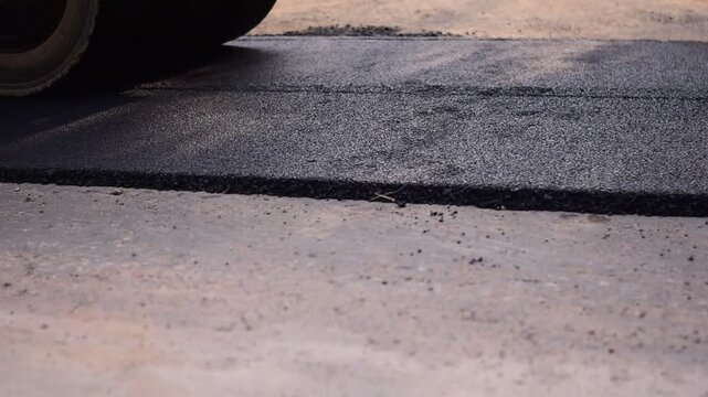 The road recycling machine is laying asphalt on the road, Pavement In-Place Recycling, Hot In-Place Recycling, Asphalt Hot Mix In-Place Recycling: Action Shot of Road Repair with Blurred Safety Cone