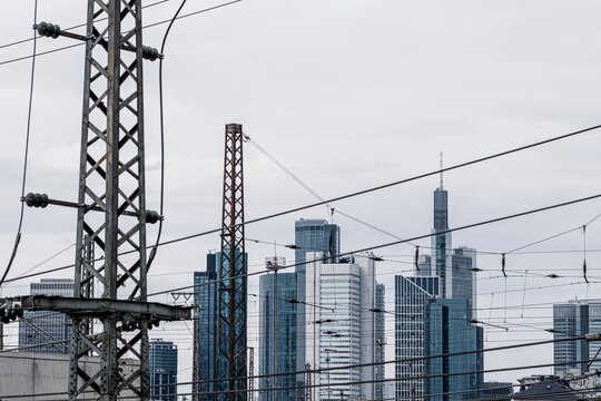 Railway wires cross urban infrastructure as office skyline rises in bankenviertel frankfurt germany suggesting transport and industry in muted light