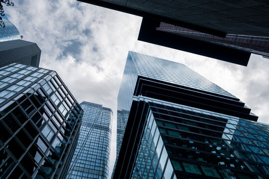 Looking upward through urban glass office architecture to a skyline of skyscraper towers in bankenviertel frankfurt germany under soft light