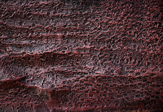 Intricate carved dark red wood texture with organic pattern and rough surface.