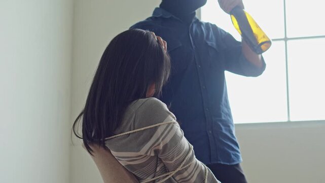 Kidnapped woman tied to chair while masked man threatens her with bottle