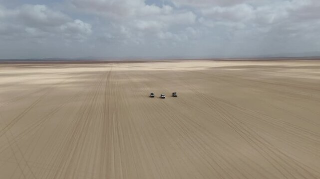 Drone view of off road driving through isolated desert landscape with wide open space, wide rotating aerial footage. Djibouti Africa.