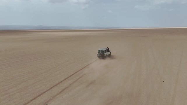 Cinematic drone shot of vehicle exploring barren terrain with long desert horizon. Djibouti Africa.