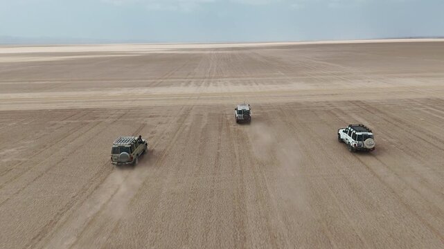 Aerial tracking shot of off road vehicle moving across remote desert with expansive open terrain. Djibouti Africa.