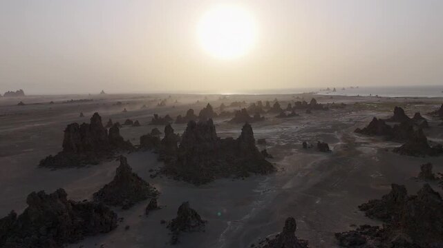 Drone view of arid terrain with rocky formations spread across desert near the Red Sea, wide aerial footage into the sun.
