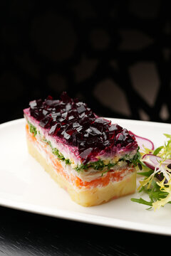 Close-up of Layered Herring Salad with Beetroot Jelly and Greens