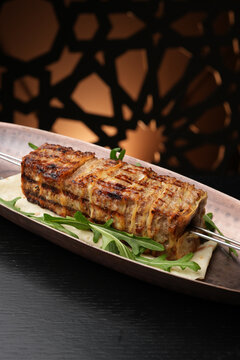 Professional Grilled Lulya Kebab Served on Metal Skewer with Arugula