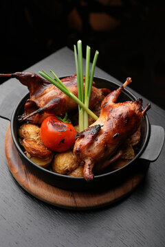 Whole Roasted Quail with Golden Potatoes and Grilled Tomato.