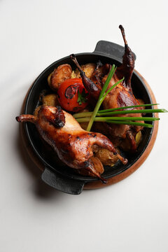 Whole Roasted Quail with Golden Potatoes and Grilled Tomato.
