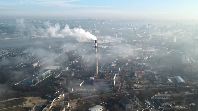 Aerial view of industrial chimney emitting smoke over foggy city landscape aerial footage.