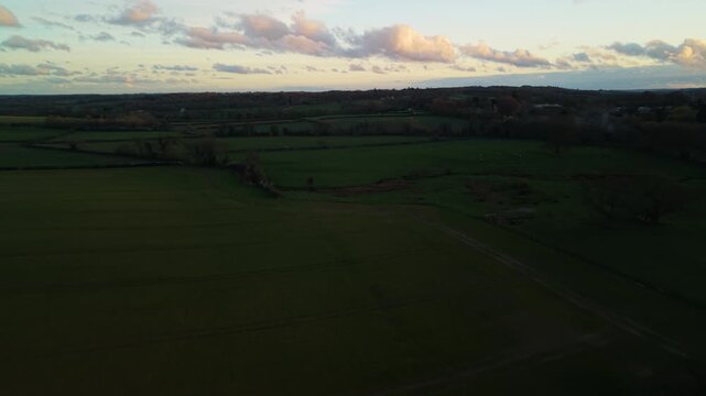 Aerial shot flying over green farmers fields in the north yorkshire countryside at dusk on a dark summers evening