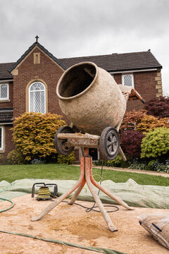 Concrete mixer in front oof garden of british house during home improvement project