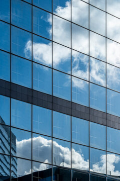 Blue sky and clouds reflected on modern glass facade building windows in office architecture for corporate business abstract background texture