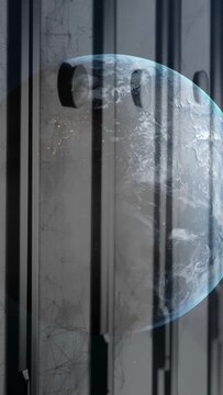 Vertical video: Pan initiating globe shifting left behind slats, revealing bluish limb and lights