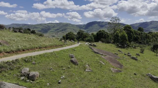 Drone flies backwards from hiker climbing Sibebe Rock on a sunny day near Mbabane, Eswatini