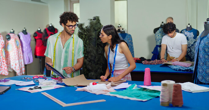 Indian young adult gen z female male man wear tape around neck use tab look screen talk share idea class room place. Tailor girl boy hold pencil do study paper create cloth craft dress learn work
