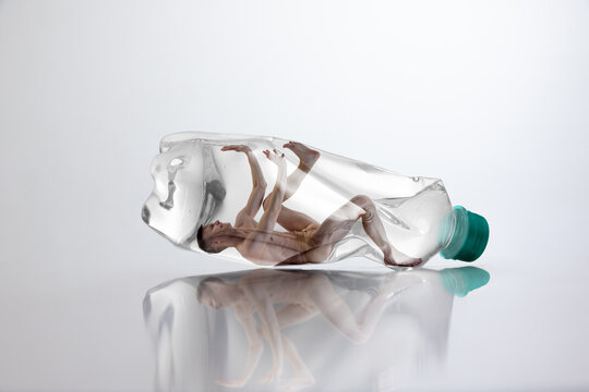 Man constrained inside plastic bottle reflecting overconsumption and loss of personal space. Concept of consumer culture pressure, environmental damage and psychological confinement.