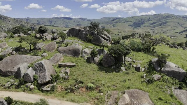 Drone rises up from hiking trail as lone dog runs by on a sunny day at Sibebe Rock near Mbabane, Eswatini