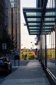 Modern minimal glass architecture along empty urban sidewalk corridor Stockholm Sweden showing quiet city passage with columns shadows and depth