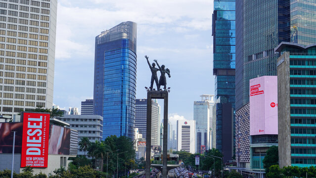 Welcome Monument (Monumen Selamat Datang) at Bundaran HI surrounded by modern skyscrapers in the business district of Jakarta, Indonesia.