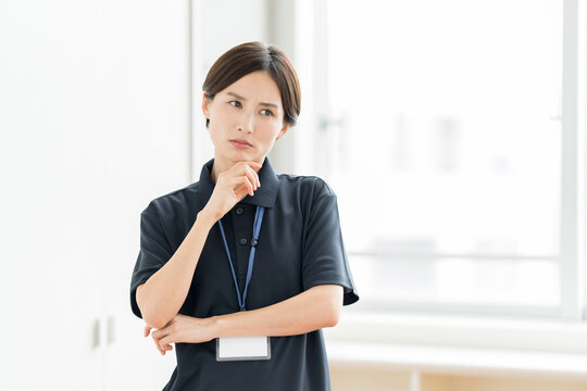 ポロシャツを着てネックストラップをかけている女性スタッフが考えている