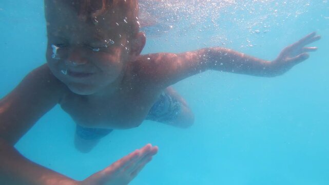 Underwater sequence showcasing a child swimming, with bubbles rising and sunlight filtering through the water, capturing the joy and freedom of aquatic exploration in a vibrant blue environment