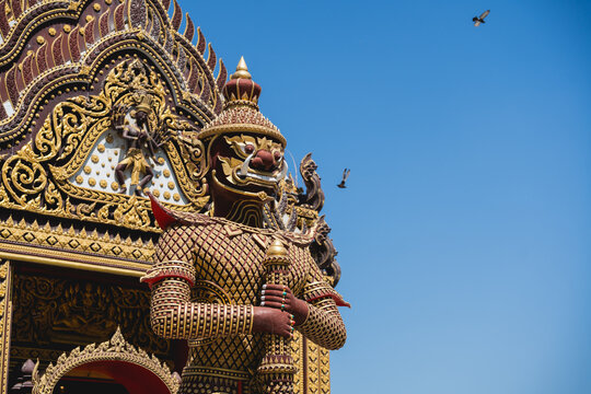 Majestic temple guardian statue with ornate details and vibrant colors against a clear blue sky, showcasing intricate craftsmanship and cultural heritage