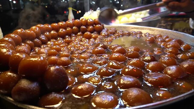 Gulab jamun soaking in syrup, glossy sweet balls in warm light, indian dessert concept