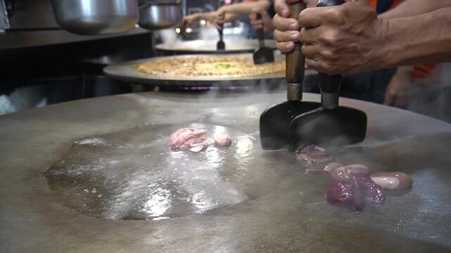 Kata-kat cooking on hot griddle with steam, meat, and spices, street cooking concept
