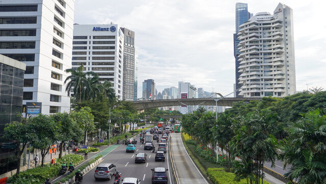View of heavy traffic congestion during afternoon rush hour on Jalan Jenderal Sudirman. Numerous cars, taxis, and motorcycles fill the road near the Karet Transjakarta bus station. Jakarta, Indonesia.