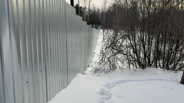 Snow cleared pedestrian path alongside highway, showing salted and grit strewn surface, high plow berm, tire tracks and compacted.