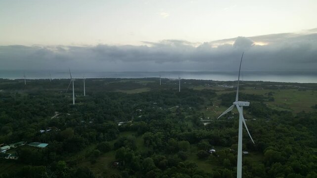 Scenic aerial view of wind turbines across tropical island landscape and lush greenery with cloudy sky - Guimaras, Visayas, Philippines