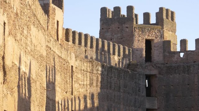 Ancient battlements and a defensive tower of Burgalimar Castle in Ba&ntilde;os de la Encina, Spain, during the golden hour.
