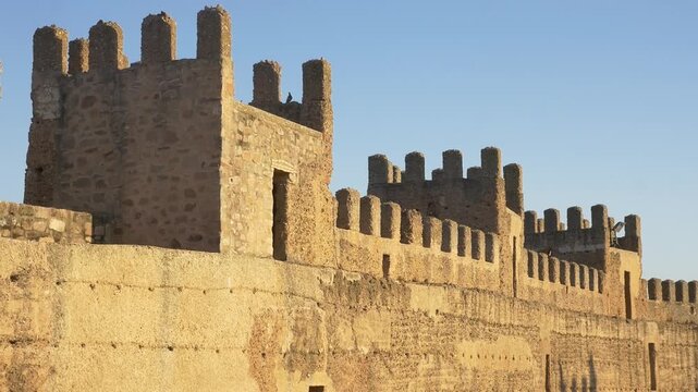Panoramic view of the well-preserved battlements and towers of the 10th-century Burgalimar Castle in Banos de la Encina, Spain, during the golden hour.