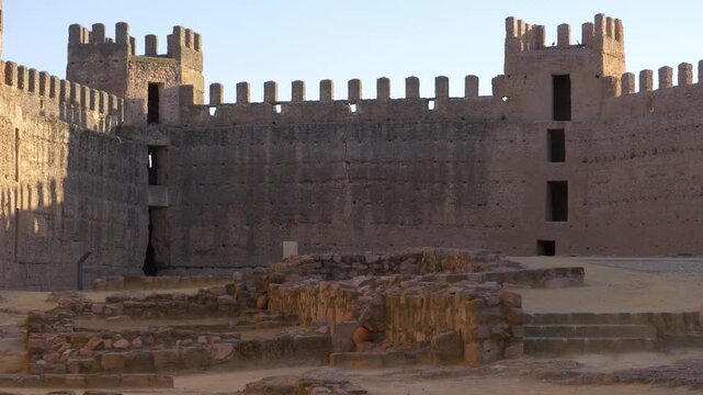 Static wide shot of the parade ground and defensive walls of the medieval Burgalimar Castle in Banos de la Encina, Spain, during the golden hour.