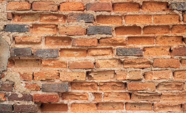 Ancient weathered red brick wall texture with cracked mortar and rustic charm.